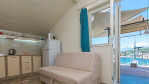 Eine kleine Küche mit Kühlschrank, Spüle und Wasserkocher auf der Arbeitsfläche.