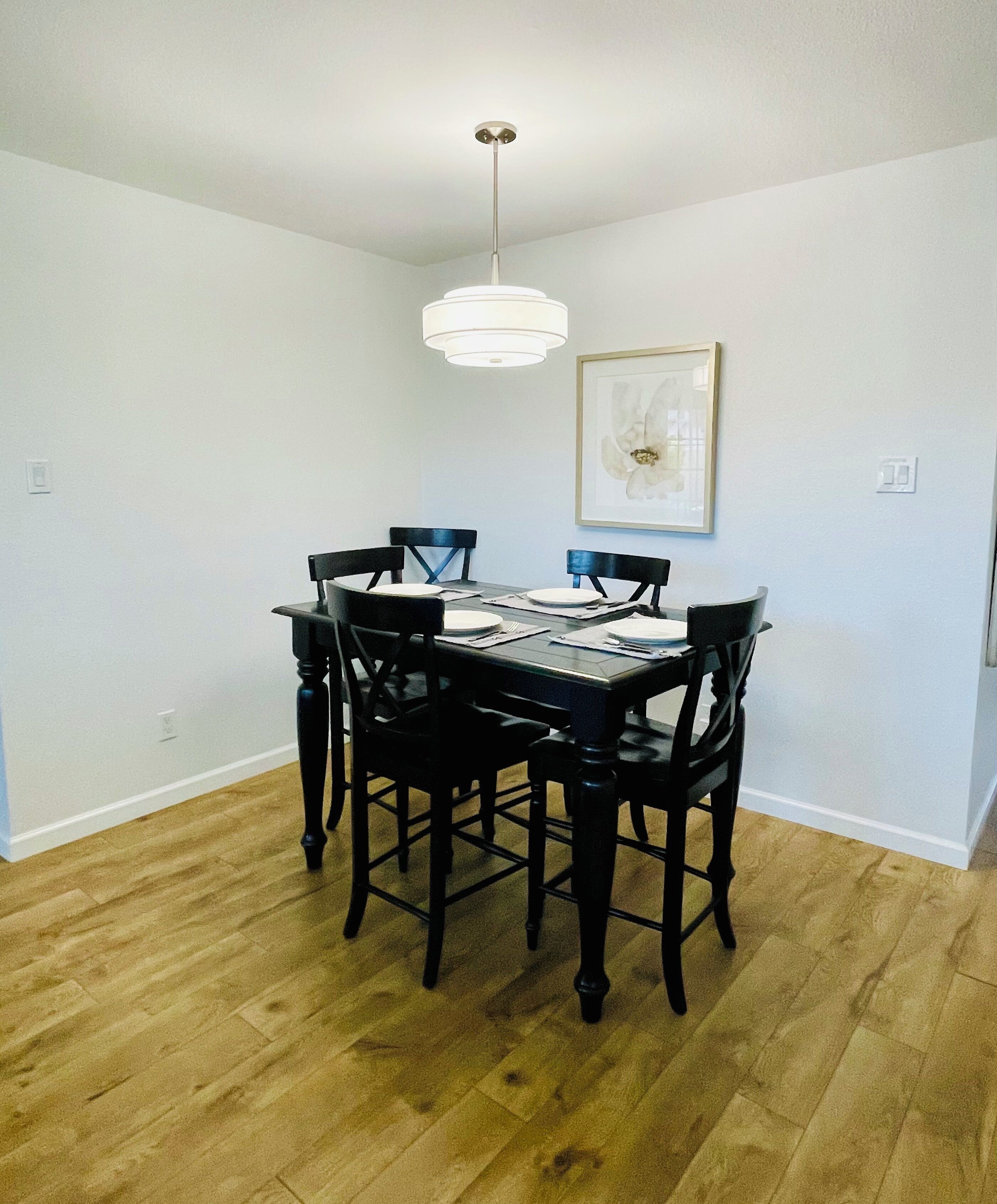 A dining area with a rectangular table, six chairs, and a hanging light fixture.