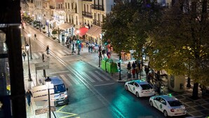 A busy urban street at night with pedestrians, taxis, and a visible TIPS van. - Hostal Venecia (Granada)