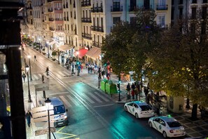 A busy urban street at night with pedestrians, taxis, and a visible TIPS van. - Hostal Venecia (Granada)