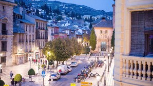 A city street with historic buildings, parked cars, and a row of motorcycles. - Hostal Venecia (Granada)