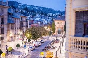 A city street with historic buildings, parked cars, and a row of motorcycles. - Hostal Venecia (Granada)