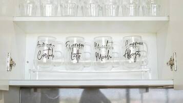 A kitchen shelf with jars labeled 'SUGAR' and 'TEA', a plant, and a tray with utensils.