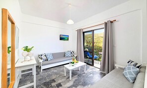 A modern living room with a grey sofa, a white coffee table, and a TV on the wall. - Villa Galini Sifis (Apokoronas)