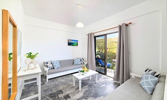 Una sala de estar moderna con un sofá gris, una mesa de centro blanca y un televisor en la pared.