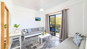 A modern living room with a grey sofa, a white coffee table, and a TV on the wall. - Villa Galini Sifis (Apokoronas)