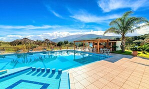 A pool area with a clear view of mountains in the background, a covered seating area, and a bar. - Villa Galini Sifis (Apokoronas)