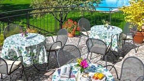 A terrace with round tables and chairs, a pool in the background, and potted plants. - Perwanger (Fie allo Sciliar)