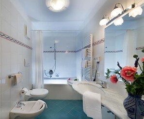 Un baño con ducha, inodoro, lavamanos y un espejo grande.