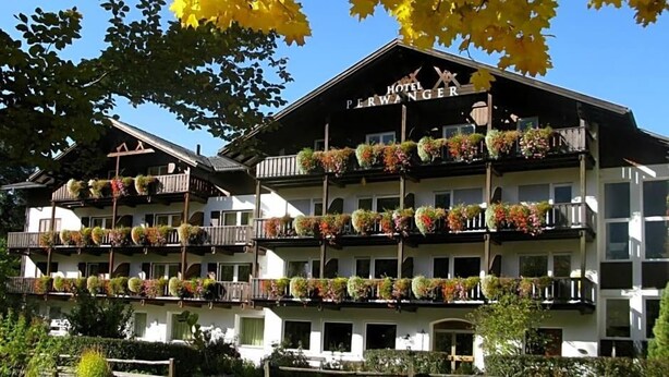 A hotel with multiple balconies adorned with flowers, a clear blue sky, and autumn leaves. - Perwanger (Fie allo Sciliar)