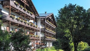 A multi-story hotel with balconies adorned with flowers, a garden area, and a clear blue sky. - Perwanger (Fie allo Sciliar)