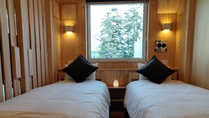 A room with two beds, wooden walls, a window with a view of trees, and wall-mounted lights. - ATTA Toya  - Lake Resort (Sobetsu)
