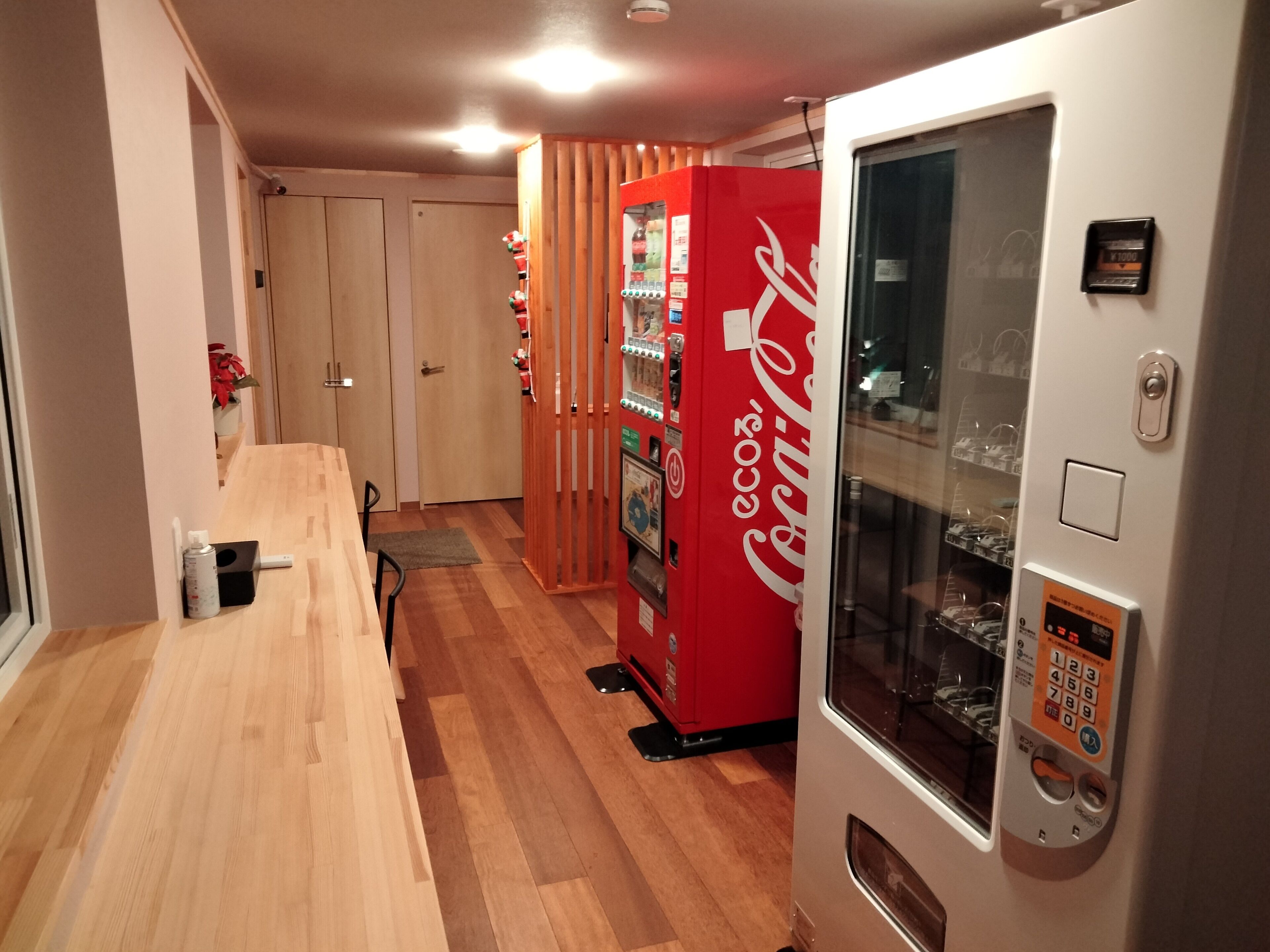 Un corridoio con pavimento in legno, una macchina distributrice e una porta vetrata con tastierino numerico.