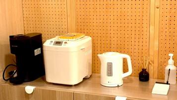 A kitchenette area with a coffee maker, a rice cooker, a kettle, and a bottle of hand sanitizer.