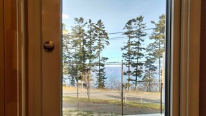 A view from a wooden door to a deck with a road and trees in the background. - ATTA Toya  - Lake Resort (Sobetsu)