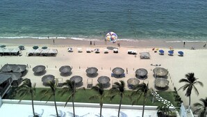 A beach with umbrellas, lounge chairs, and palm trees. - Wohnung mit Whirlpool by Interhome (Acapulco de Juarez)
