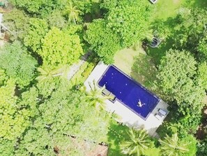 Vue aérienne d’une propriété dotée d’une piscine, entourée d’une végétation luxuriante.