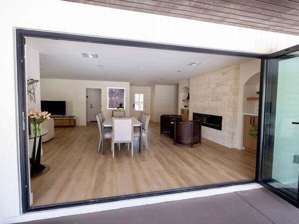 Un intérieur moderne comprenant un coin repas, une cheminée et une grande porte vitrée donnant sur un espace extérieur.