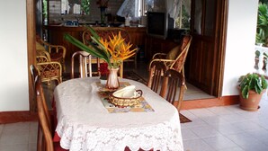A dining area with a table set for two, surrounded by wooden chairs, a vase with flowers, and a decorative plate. - Erdgeschosswohnung mit Grill in Mare Anglaise by Interhome (Beau Vallon)