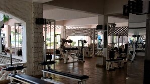 Un gimnasio con bancos, máquinas de pesas y un espejo grande.