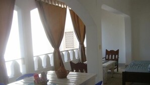 Un comedor con una mesa blanca, sillas azules y una ventana con cortinas.