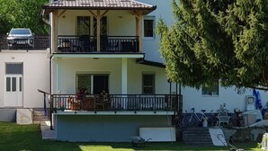 Un edificio de dos pisos con un balcón, un césped al frente y una bicicleta estacionada.