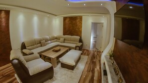 Una sala de estar moderna con un sofá modular, una mesa de centro y un televisor de pantalla plana montado en la pared.
