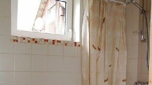 Ein Badezimmer mit Dusche, Toilette und Fenster.