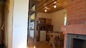 Eine rustikale Küche mit Holzböden, einem Kamin aus Backsteinen und einer Holzbalkendecke.