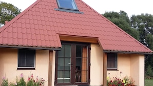 A house with a red-tiled roof, a wooden door, and a small porch with steps. - Fuchsbau in Waldnähe by Interhome (Kuldiga)