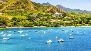 A coastal area with boats on clear blue water, a beach, and a hillside with buildings. - "Casa Meloso" mit eigenem Pool by Interhome (Huacas)