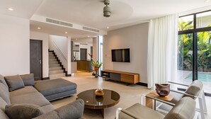 Ein modernes Wohnzimmer mit einem Ecksofa, einem Couchtisch und einem an der Wand befestigten Fernseher.