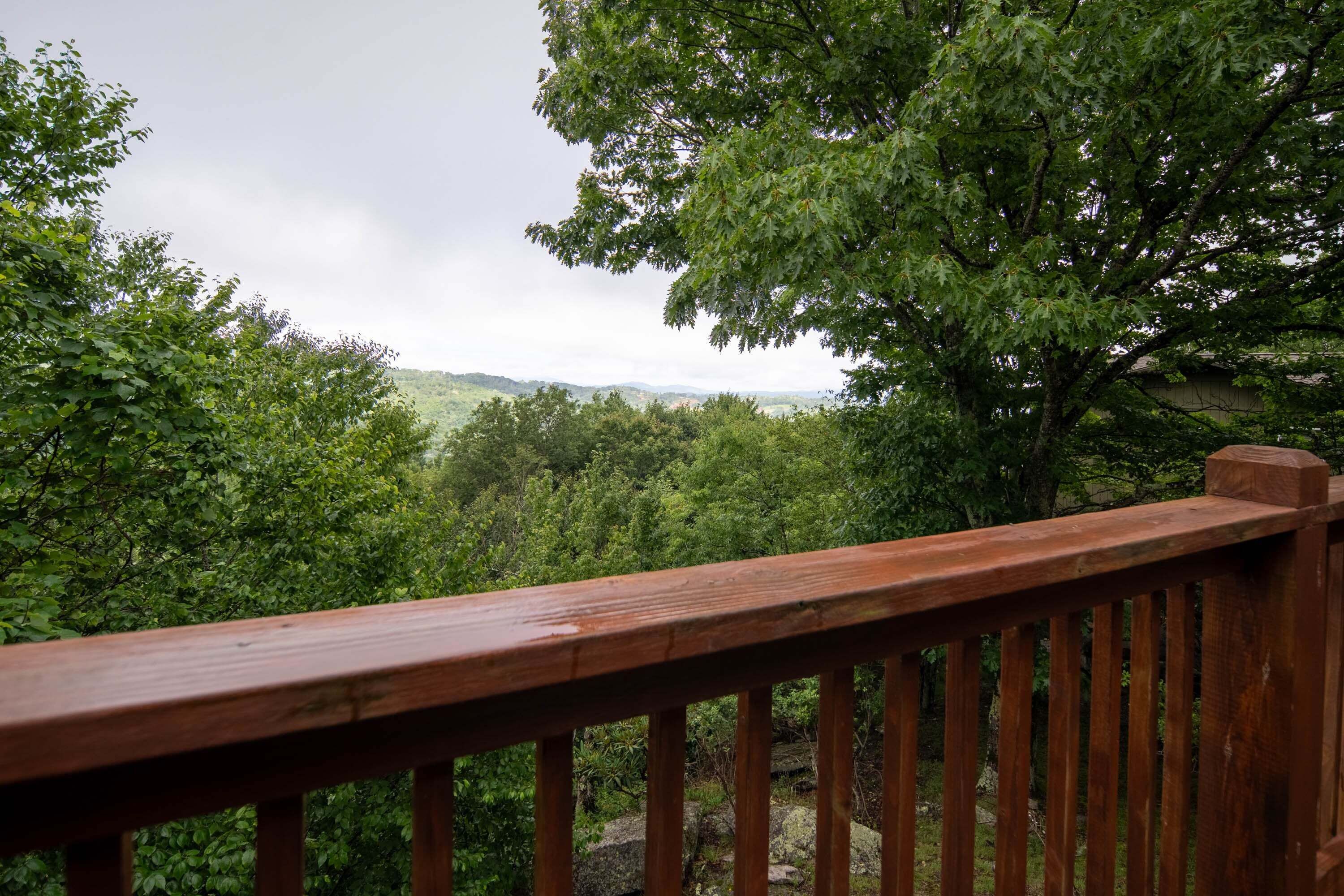 A wooden deck with a view of a forested landscape.