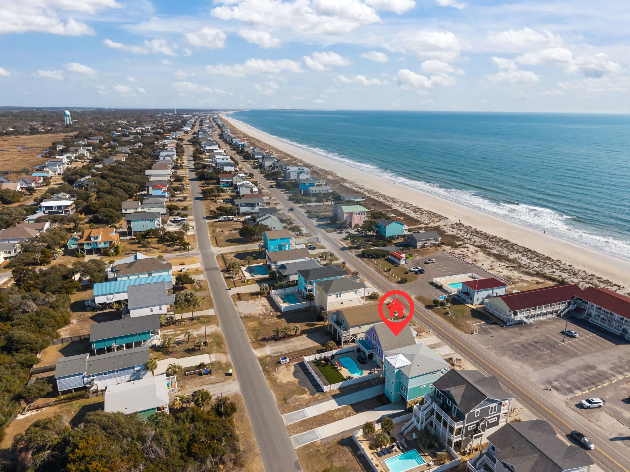An aerial view of a coastal residential area with houses, a beach, and a water tower.