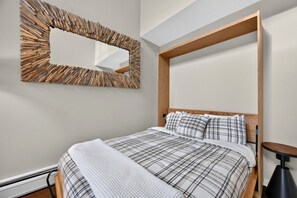 Ein modernes Schlafzimmer mit einem Bett, einem hölzernen Kopfteil, einem großen Spiegel und einem Nachttisch.