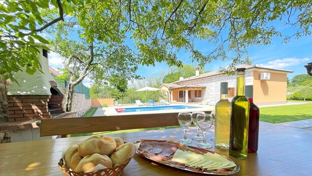 A table with bread, cheese, and wine glasses, overlooking a pool and a house. - Villa Balarini (Istria - Labin) (Šumber)