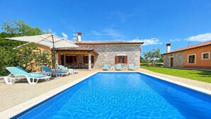 A swimming pool with lounge chairs, a stone building with a tiled roof, and a clear blue sky. - Villa Balarini (Istria - Labin) (Šumber)