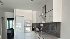 Una cucina moderna con mobili bianchi, forno integrato e piano di lavoro in marmo.