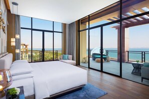 A spacious bedroom with a large bed, a balcony with a view of the sea, and a cityscape in the background. - Yongan Hotel (Sanming)