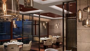 A modern dining area with multiple tables, hanging pendant lights, and a view of the cityscape through large windows. - Yongan Hotel (Sanming)