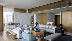 A spacious living room with a large sectional sofa, a coffee table, and a seating area with a small table and chairs. - Yongan Hotel (Sanming)