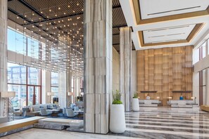 A spacious lobby with a high ceiling, large windows, and a reception desk. - Yongan Hotel (Sanming)