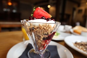 A dessert in a glass bowl with a strawberry on top, served on a plate. - Olde Kings Arms (Hemel Hempstead)