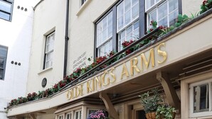 Μια παμπ με το όνομα «The Old Kings Arms», η οποία διαθέτει καθιστικά σε εξωτερικό χώρο και κρεματά καλάθια με λουλούδια.