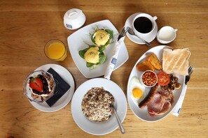 A breakfast spread with various dishes including eggs, toast, beans, and a glass of orange juice. - Olde Kings Arms (Hemel Hempstead)