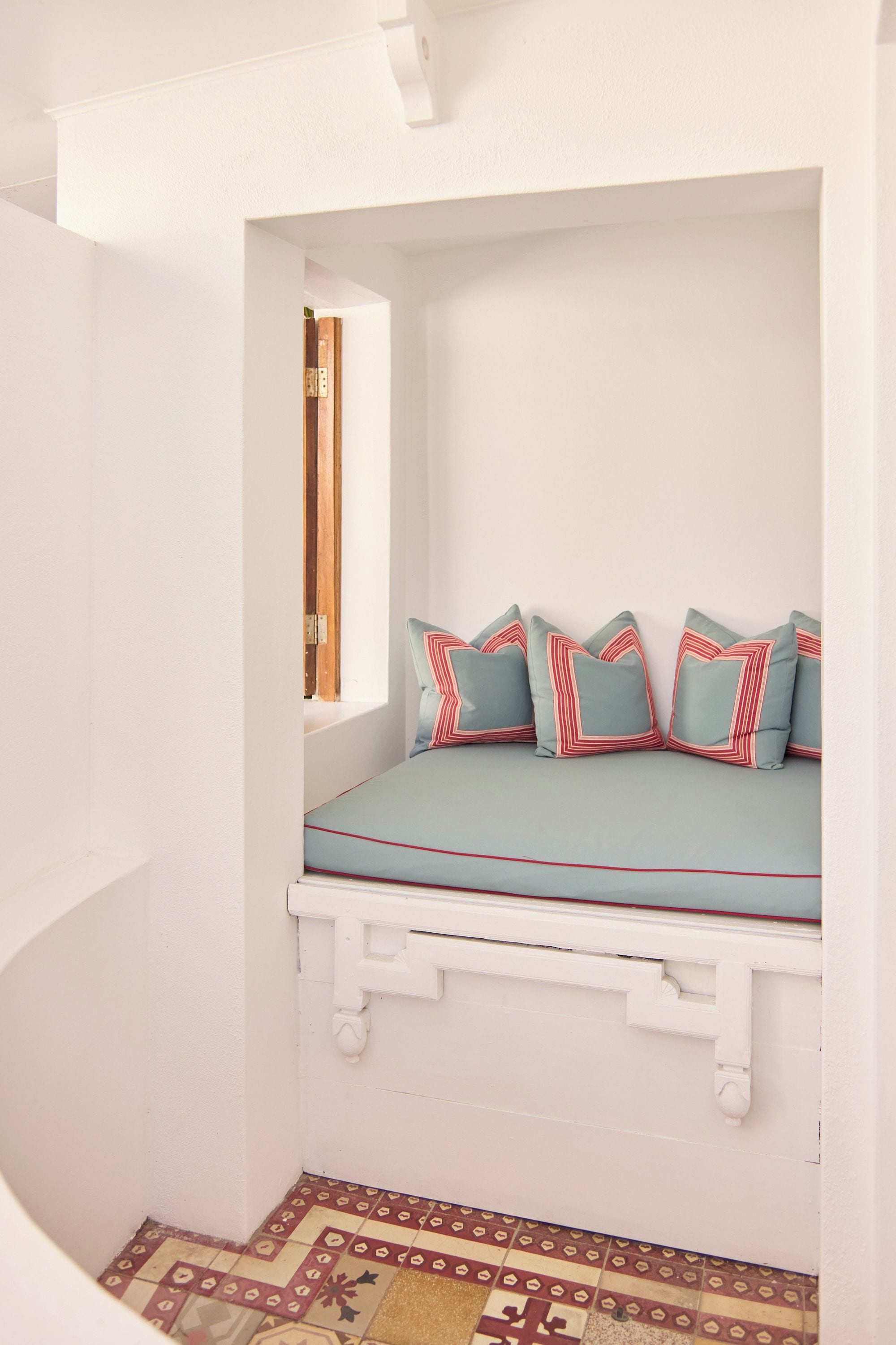A room with a built-in bench, a window, and patterned flooring.
