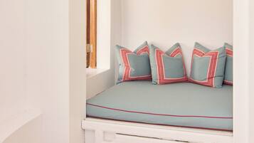 A room with a built-in bench, a window, and patterned flooring.