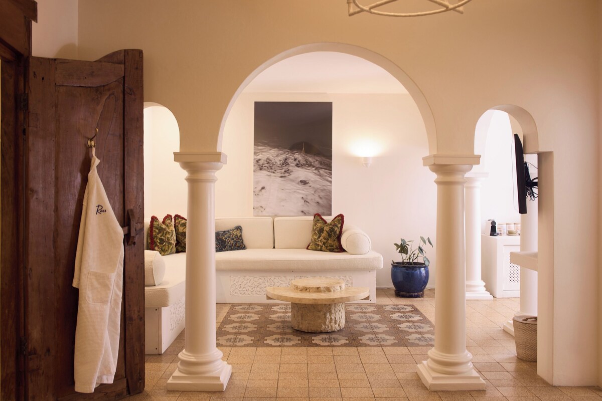 A room with a white sofa, a wooden door, and a painting on the wall.