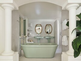 Un baño con una bañera independiente, dos lavamanos y dos espejos.