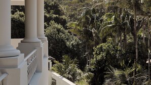 A poolside view with a view of a lush tropical garden and a white building with columns. - Raes on Wategos  (Byron Bay)